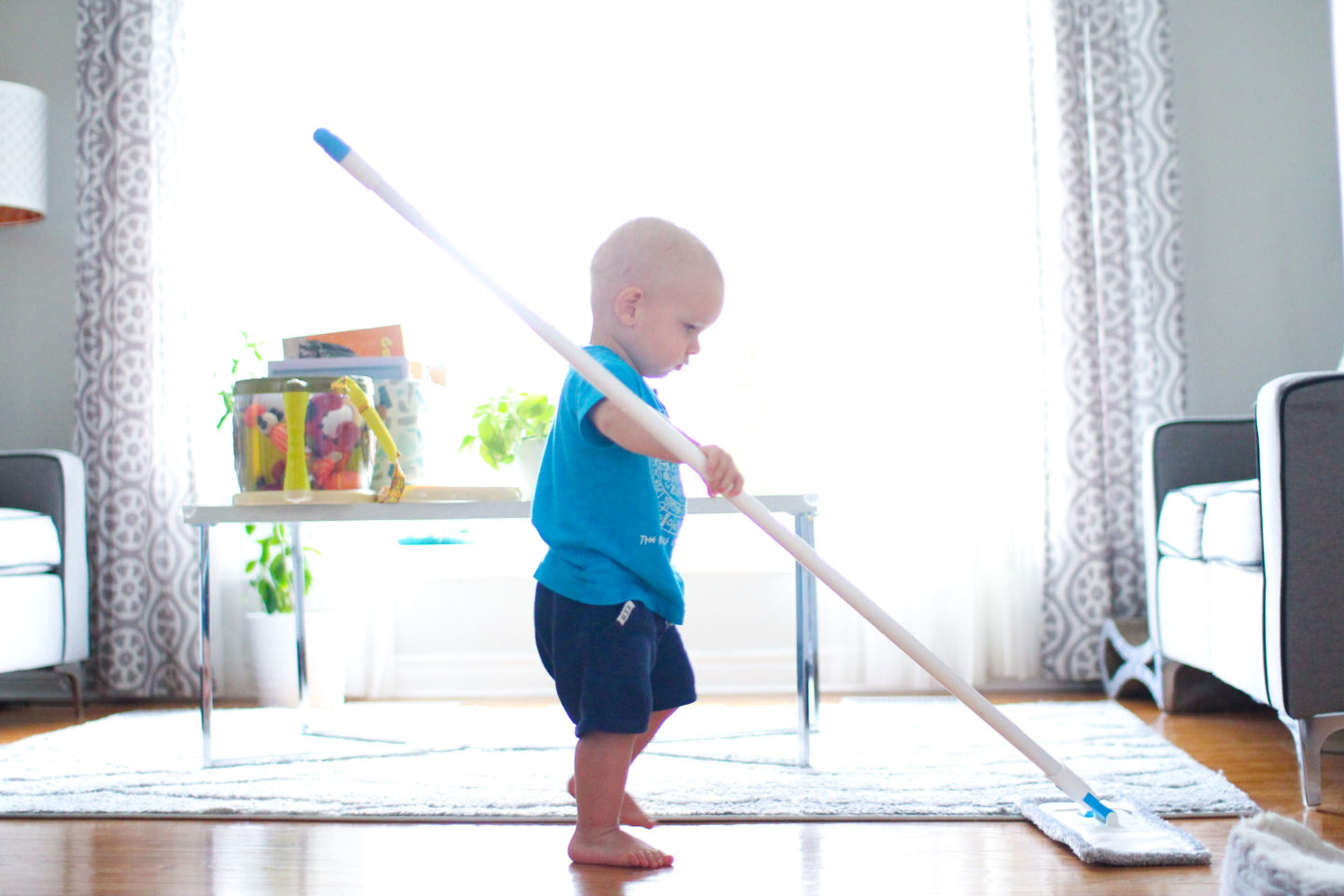 toddler boy focused on mopping the floor in a Montessori home