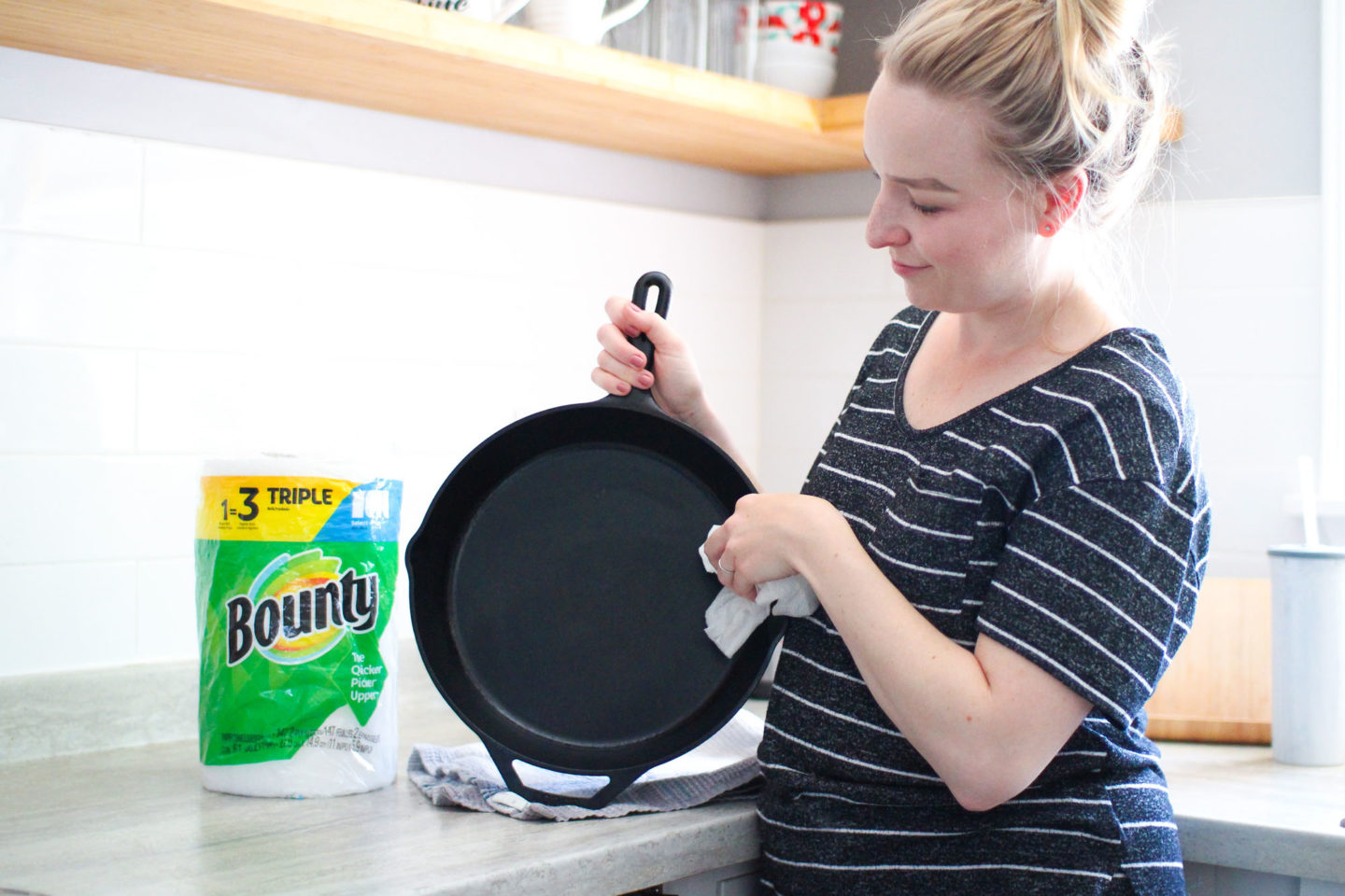 woman drying cast iron skillet with paper towels 
