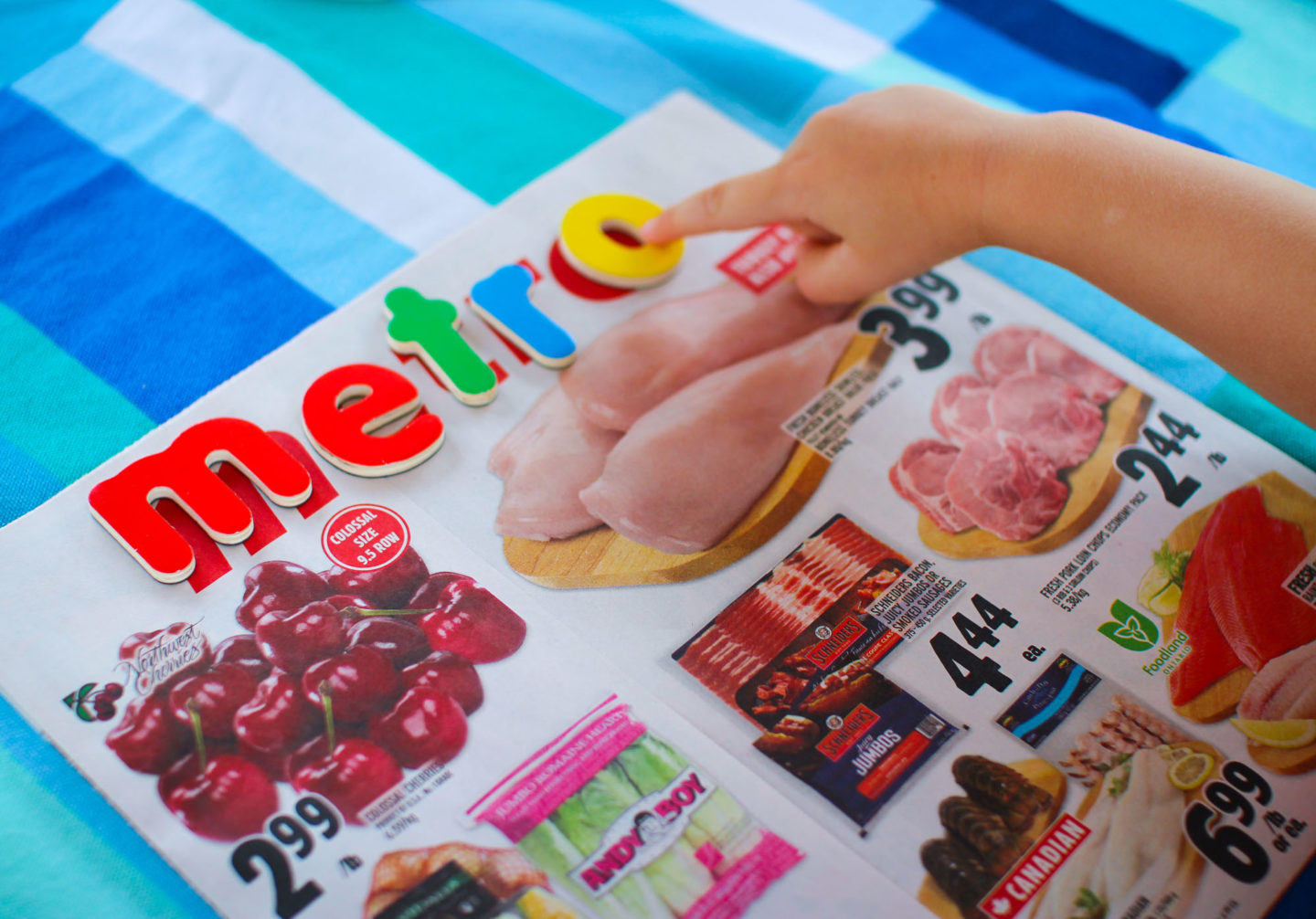 toddler activity placing alphabet magnets on grocery flyer