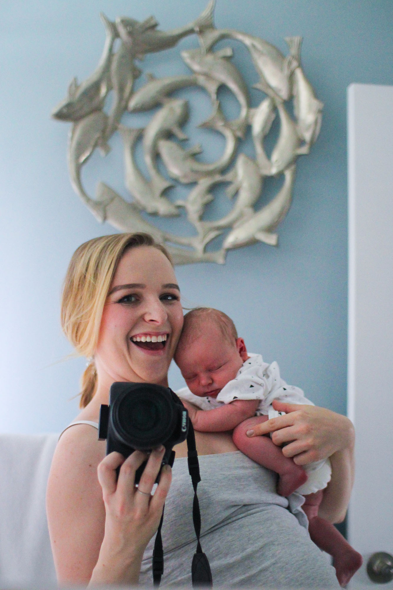 postpartum mom taking selfie in mirror with newborn baby