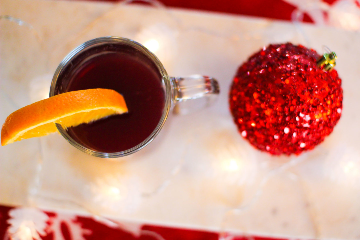 mulled wine with an orange slice in a mug amogst holiday decor