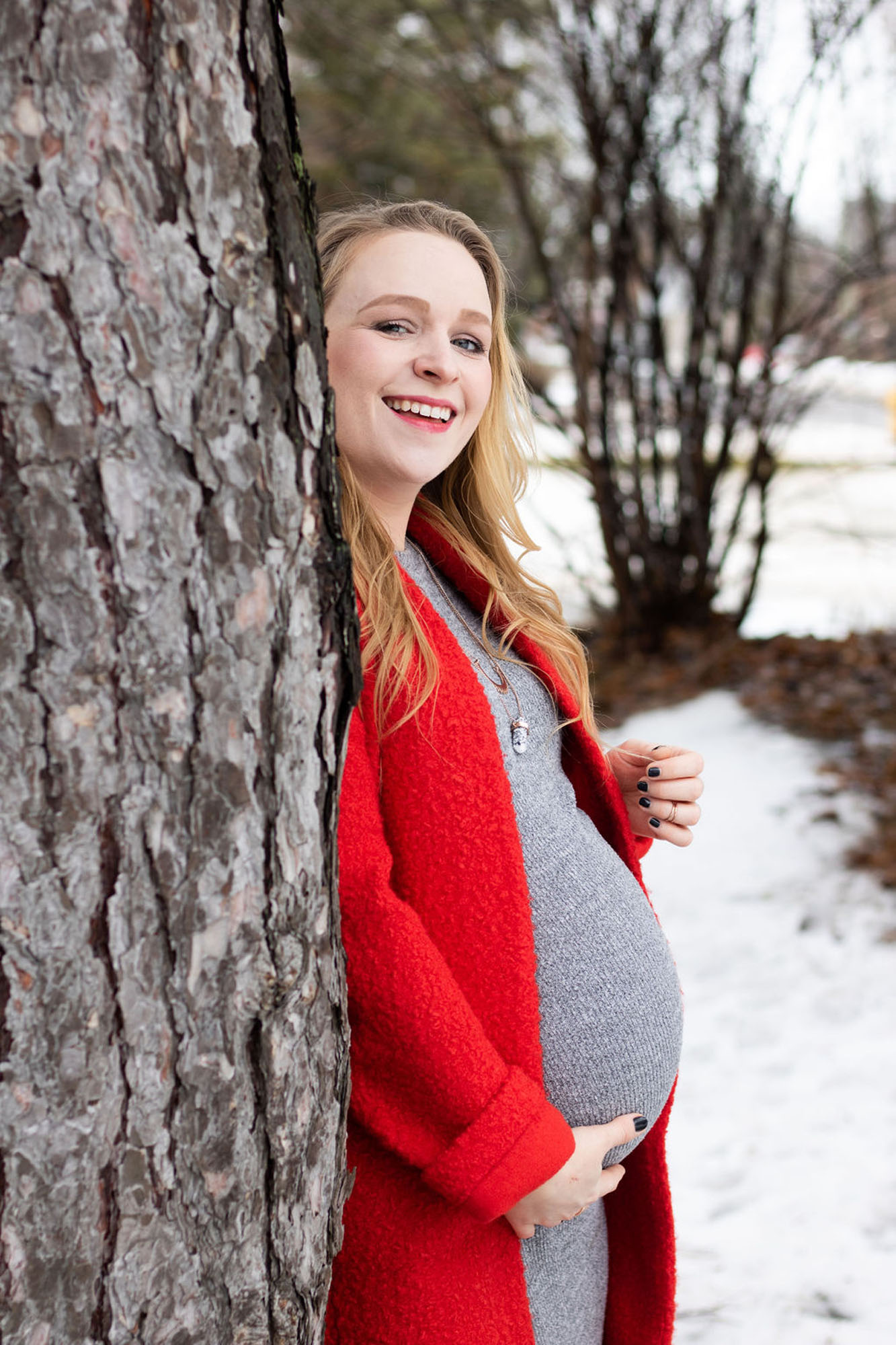 pregnant woman outside near tree in the winter