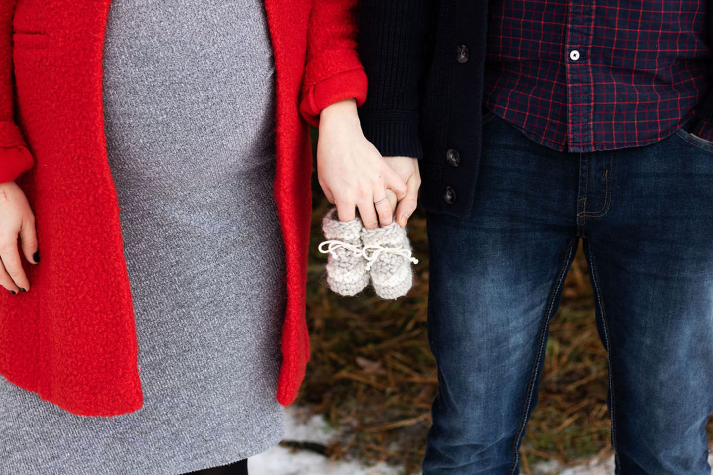 pregnant couple holding baby shoes 