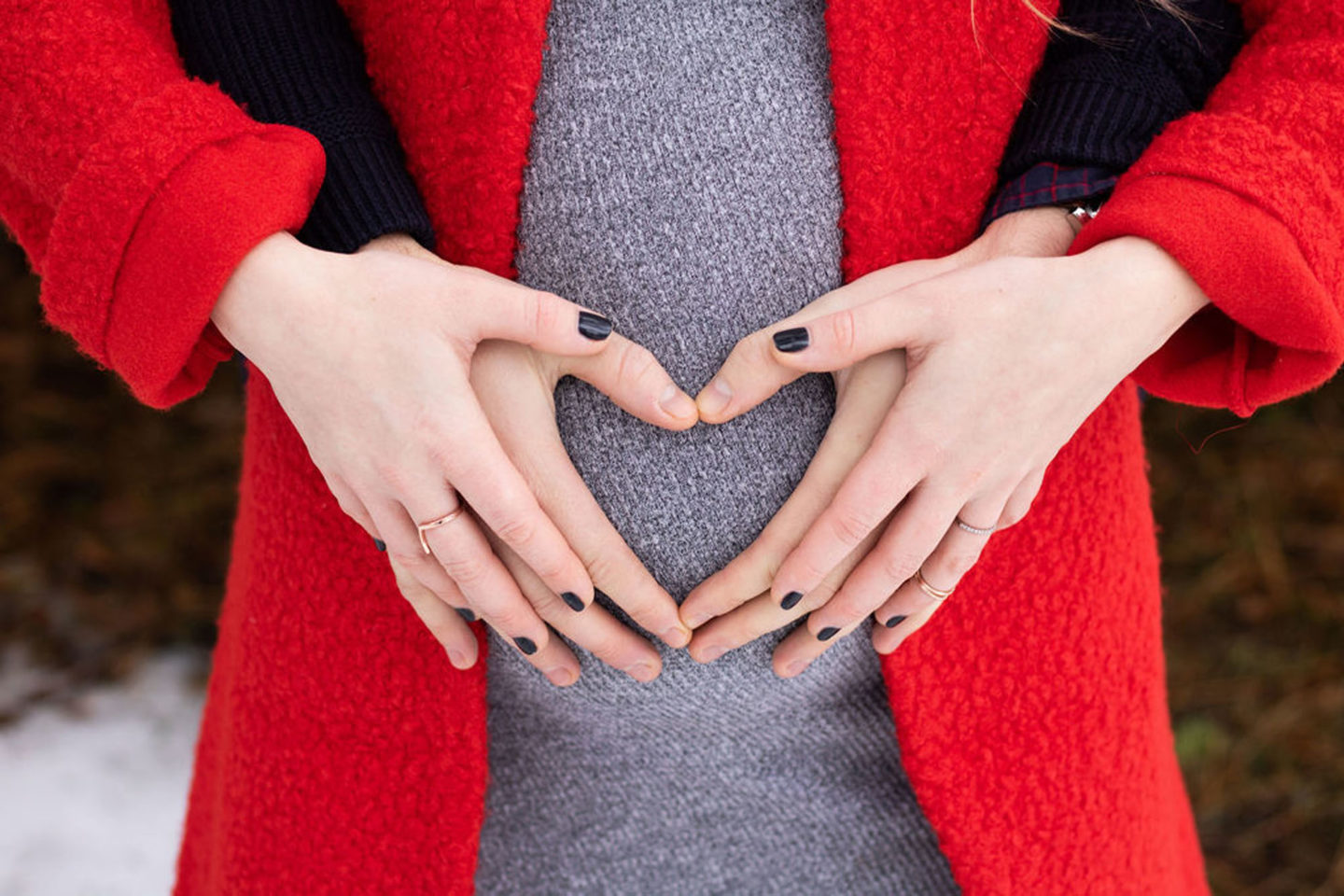 husband and wife hands over a pregnant belly 